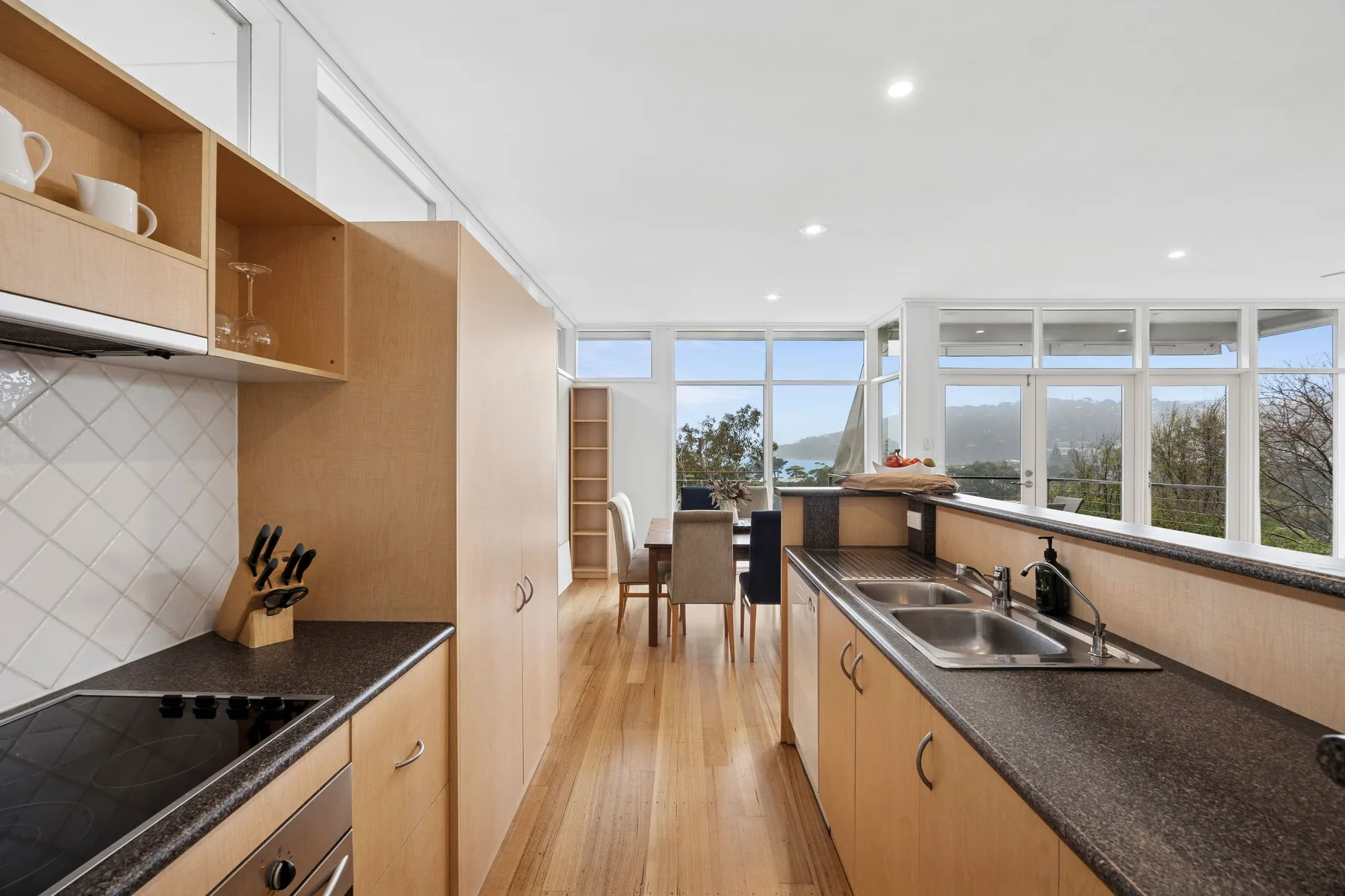 Una cocina luminosa con una encimera larga y grandes ventanas.