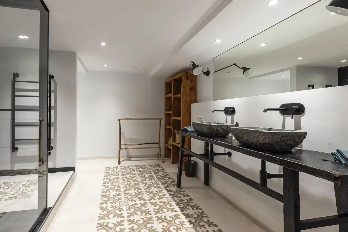 A spacious bathroom features a long vanity with vessel sinks and a patterned floor runner.