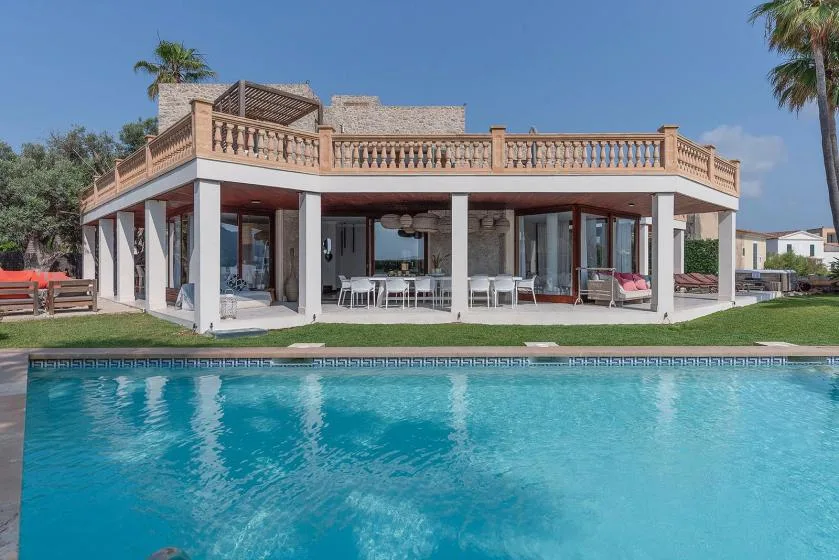 A modern house with a covered patio stands beside a swimming pool.