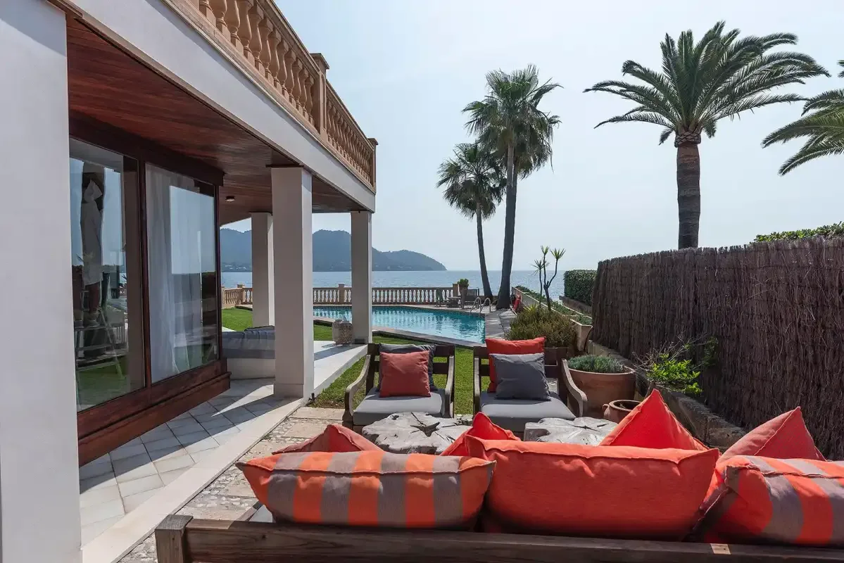 A patio seating area overlooks a pool and the sea.