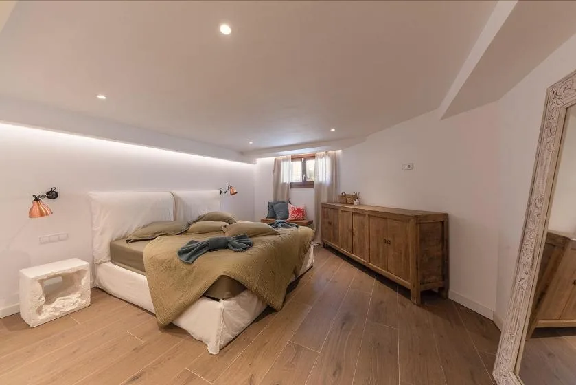 A bedroom with a double bed, bedside tables, and a wooden dresser.