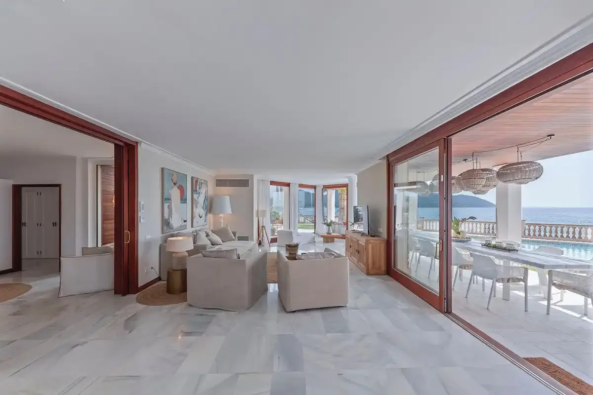 A bright living area opens onto a dining space beside large glass doors.