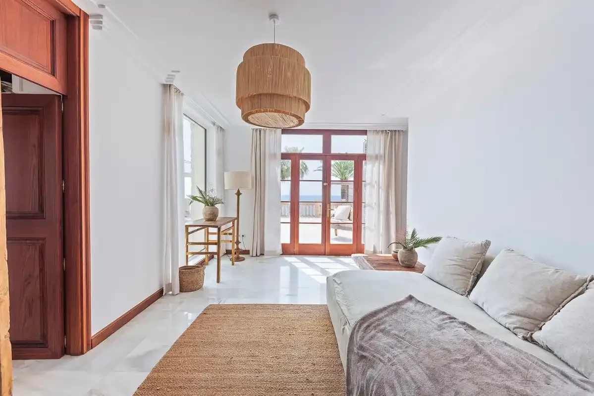 A bright living room with a seating area and glass doors opening to a balcony.