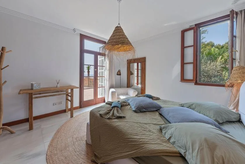 A bright bedroom with a low bed and large open windows.