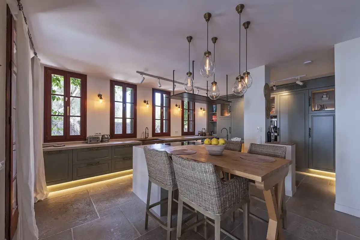 A spacious kitchen and dining area with a wooden table and pendant lights.