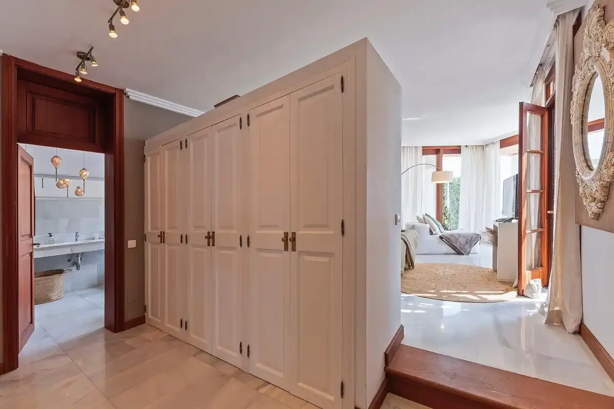 A hallway with built-in cabinets opens onto a bright sitting area.
