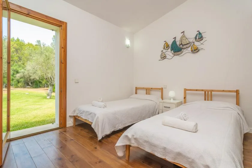 Un dormitorio con dos camas y una gran ventana con vistas a la vegetación.
