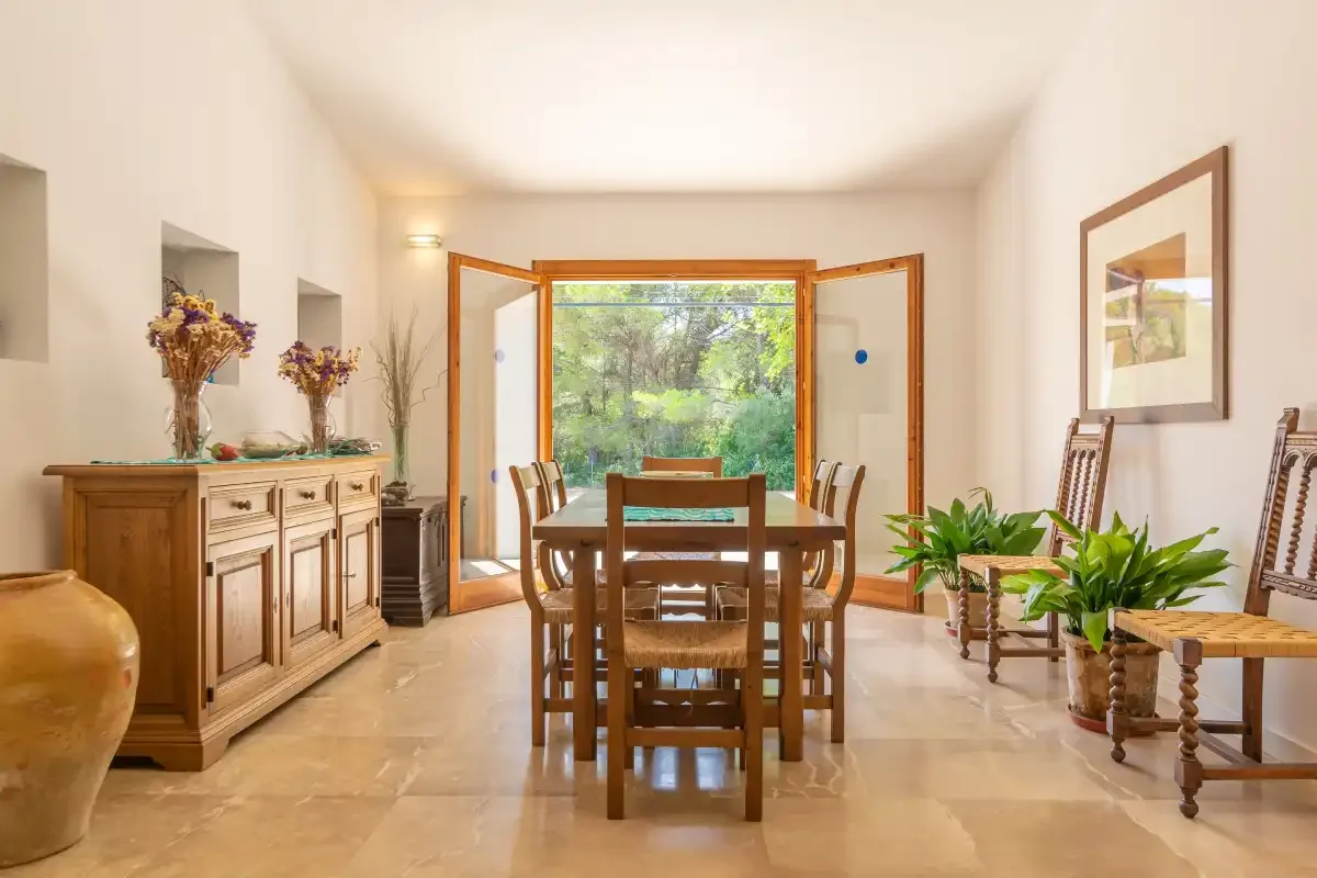 Un comedor luminoso con una mesa de madera y puertas abiertas al jardín.
