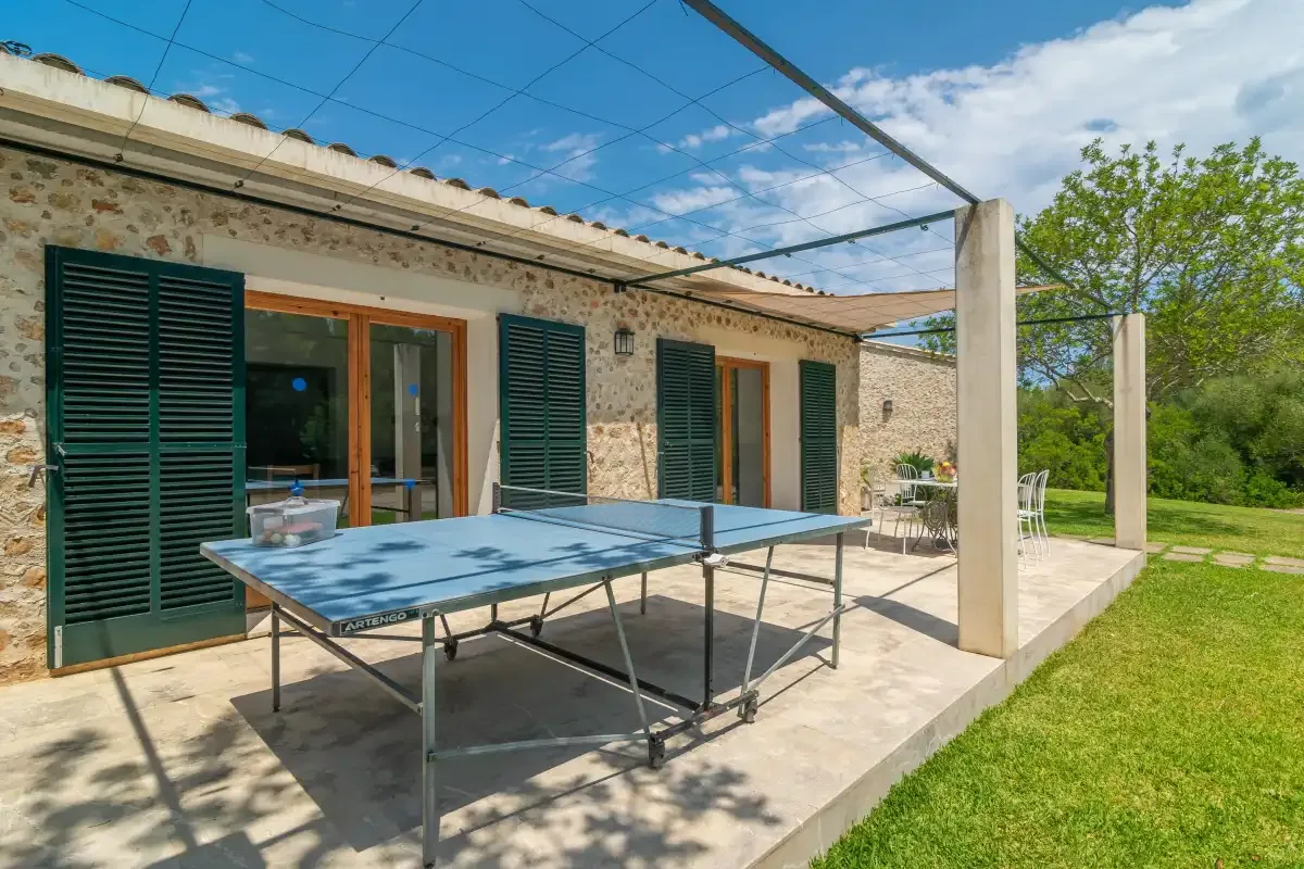 Un patio de piedra tiene una mesa de ping-pong junto al césped.