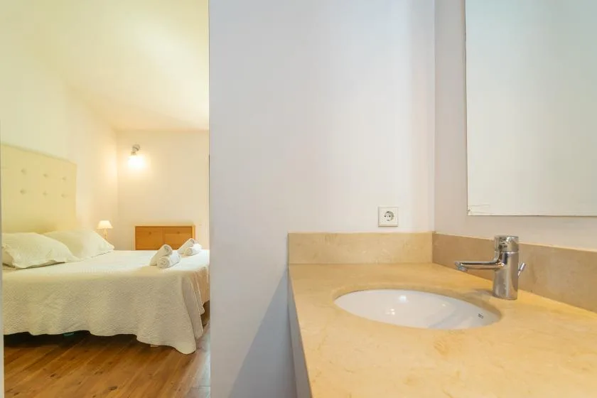 Se ven un dormitorio y un tocador de baño contiguo con lavabo.