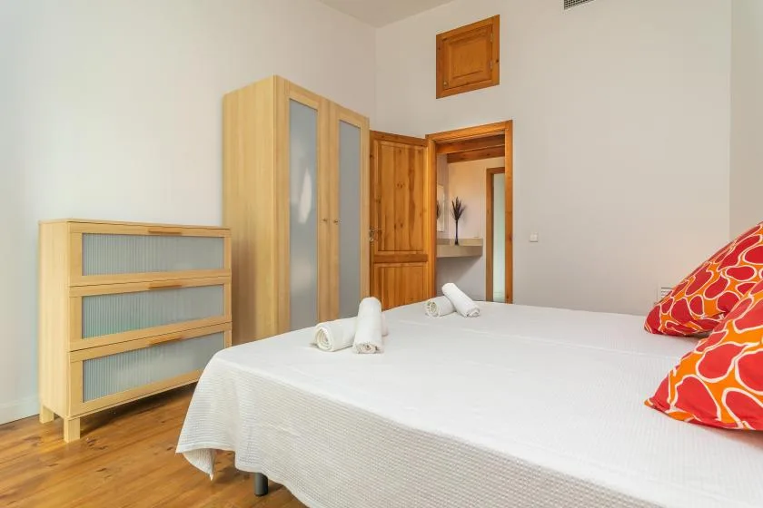 Un dormitorio con una cama blanca, muebles de madera y una puerta de madera.