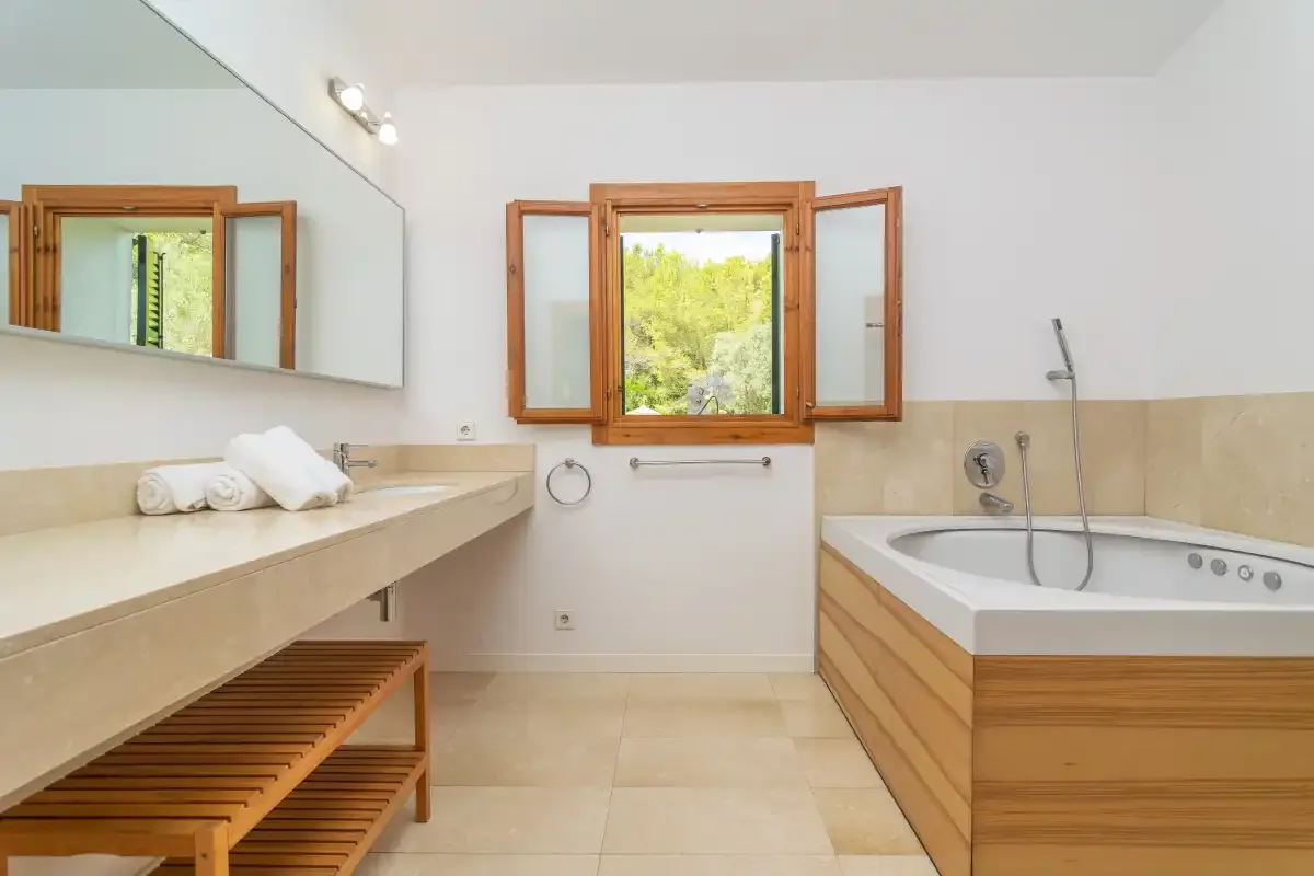 Un baño luminoso con una bañera revestida de madera y un espejo grande.