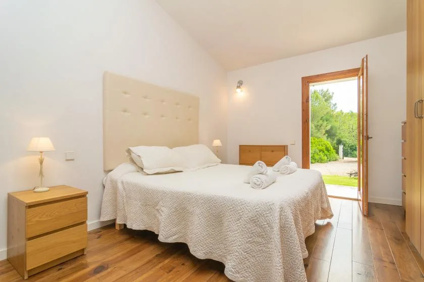 Un dormitorio con una cama junto a una puerta abierta con vistas a la vegetación.