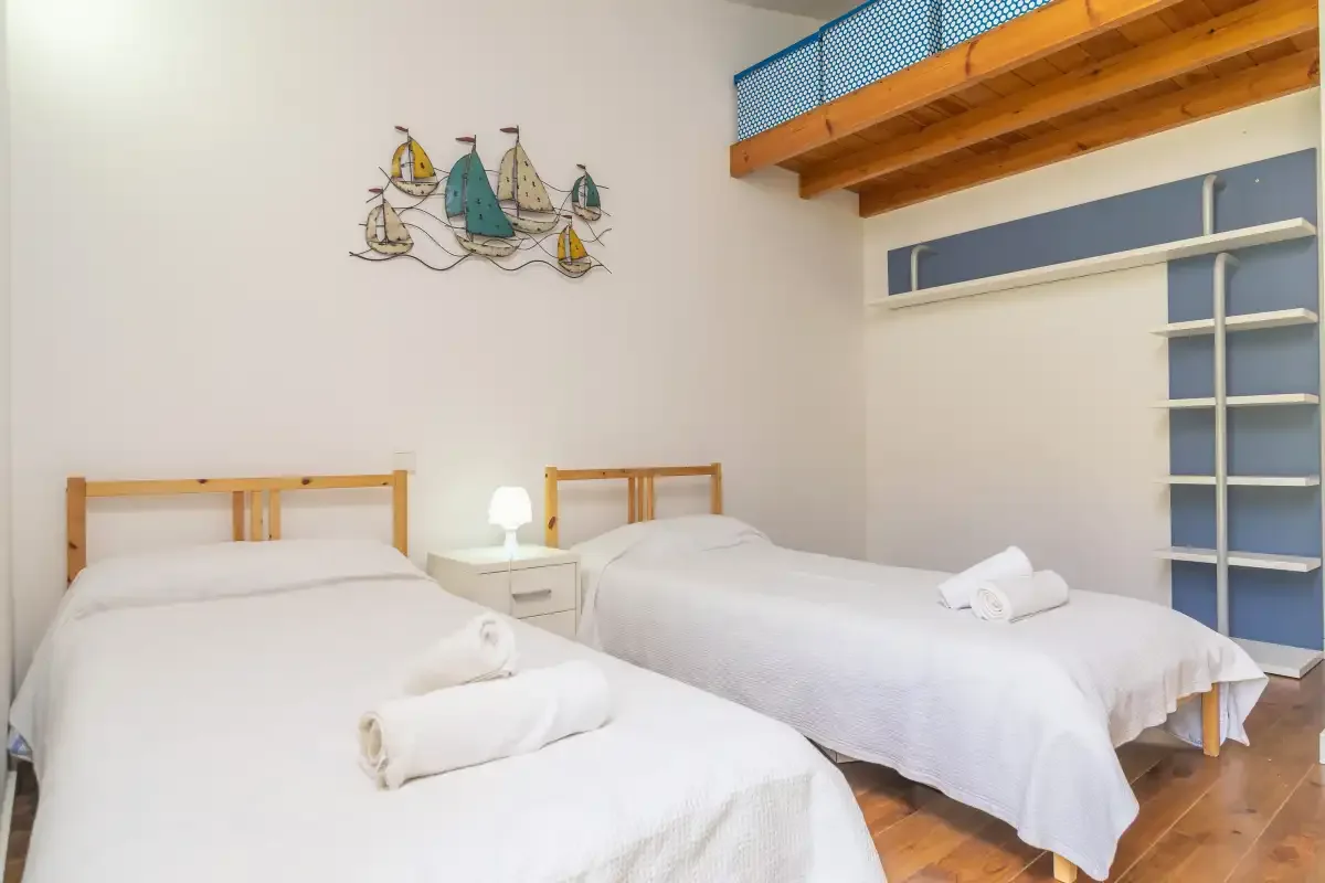 Un dormitorio con dos camas y un altillo de madera encima.
