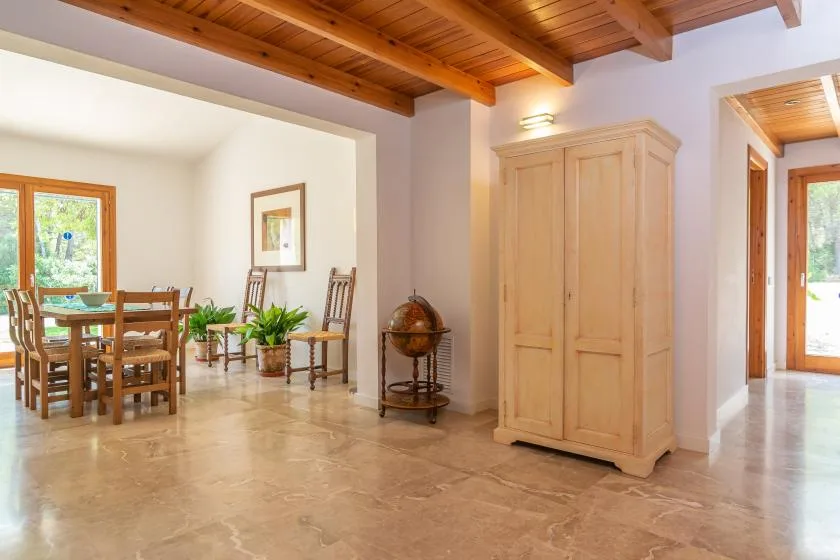 Un comedor luminoso con asientos de madera, un armario grande y vigas de techo expuestas.