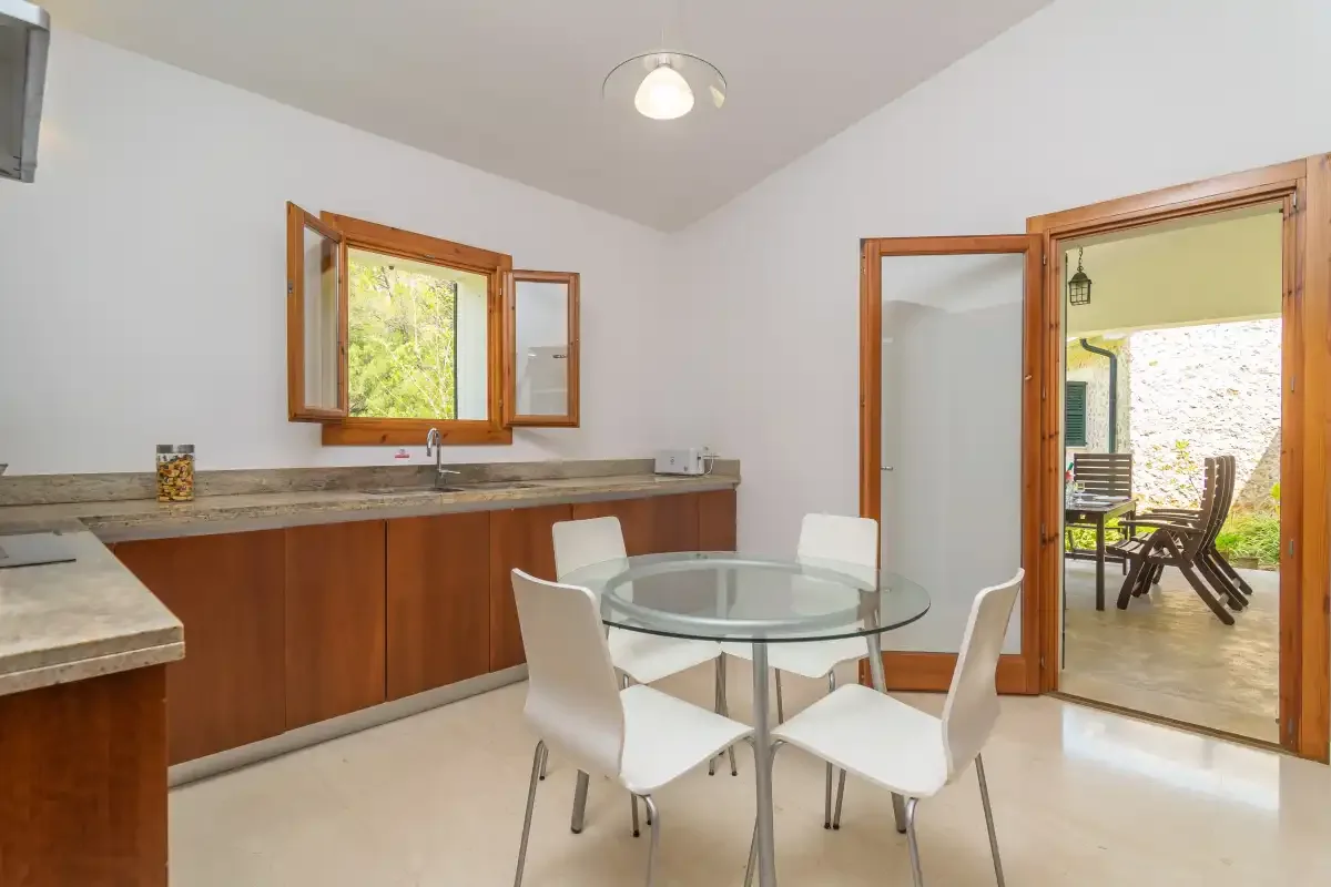 Un comedor luminoso con una mesa de cristal junto a una puerta abierta al patio.