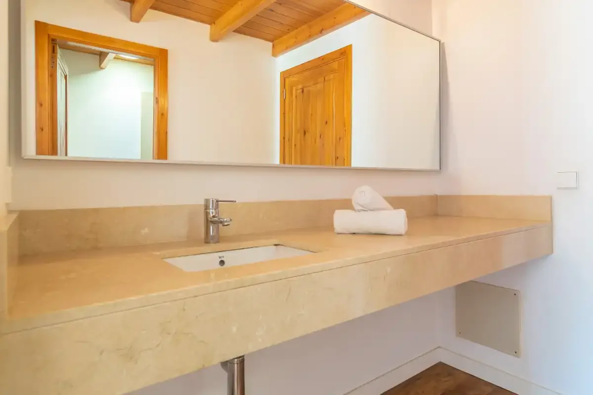Un baño luminoso con un largo lavabo, un fregadero y un gran espejo de pared.