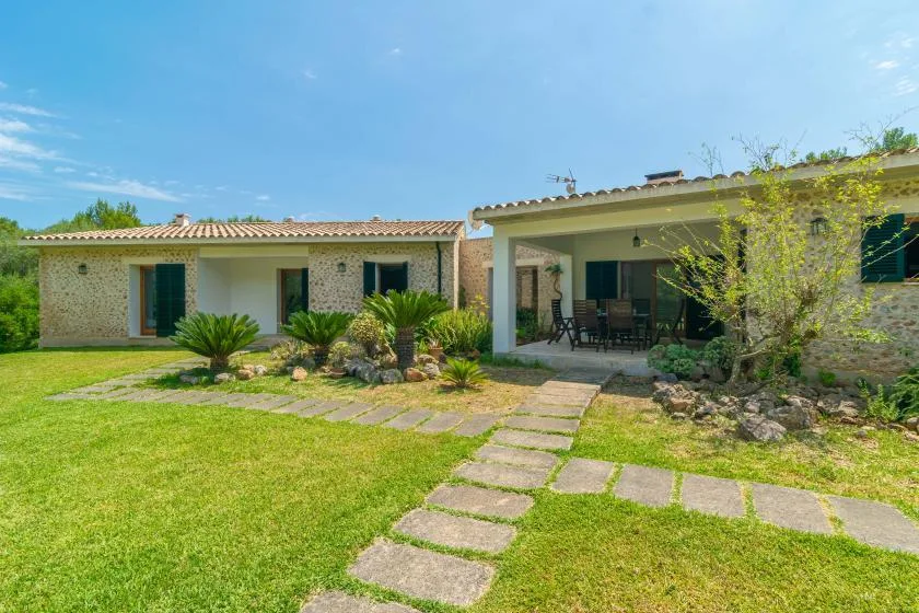 Casa de una planta con patio cubierto, jardín y sendero de piedra.