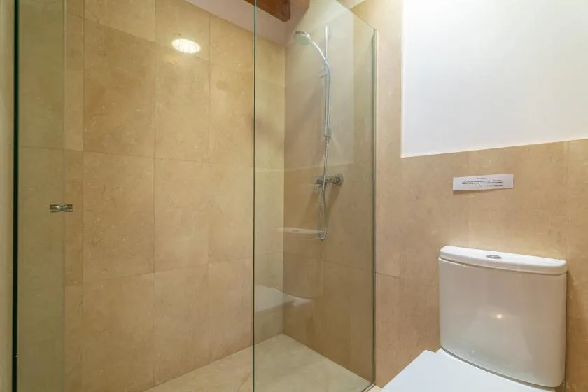Un baño con azulejos, ducha de vidrio e inodoro.