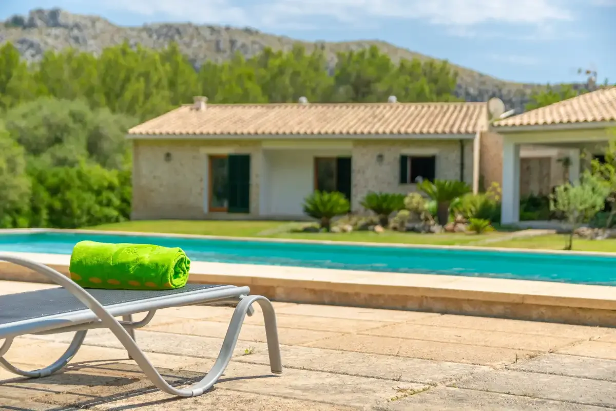 Una piscina y asientos de descanso están frente a un edificio bajo de piedra.