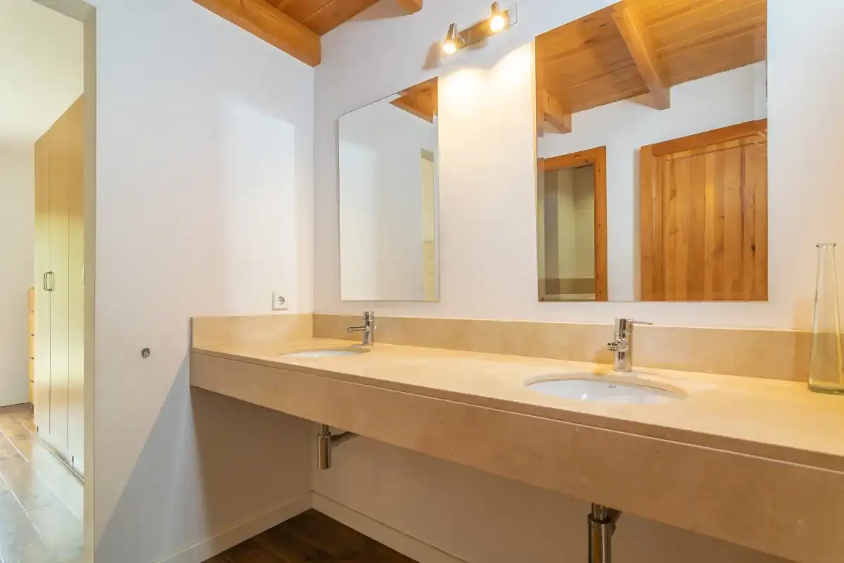 Un lavabo de baño con dos lavabos está debajo de un gran espejo.