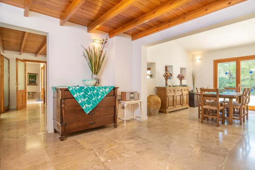 Un comedor luminoso con una mesa de madera bajo un techo de vigas.