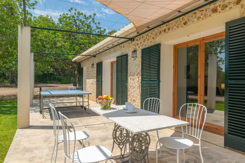 Una terraza exterior soleada con mesa y sillas junto a un edificio con fachada de piedra.