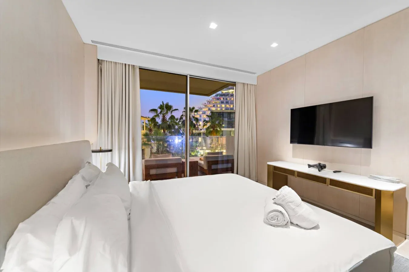 Un dormitorio con una cama bien tendida y una ventana grande con vistas a la ciudad.