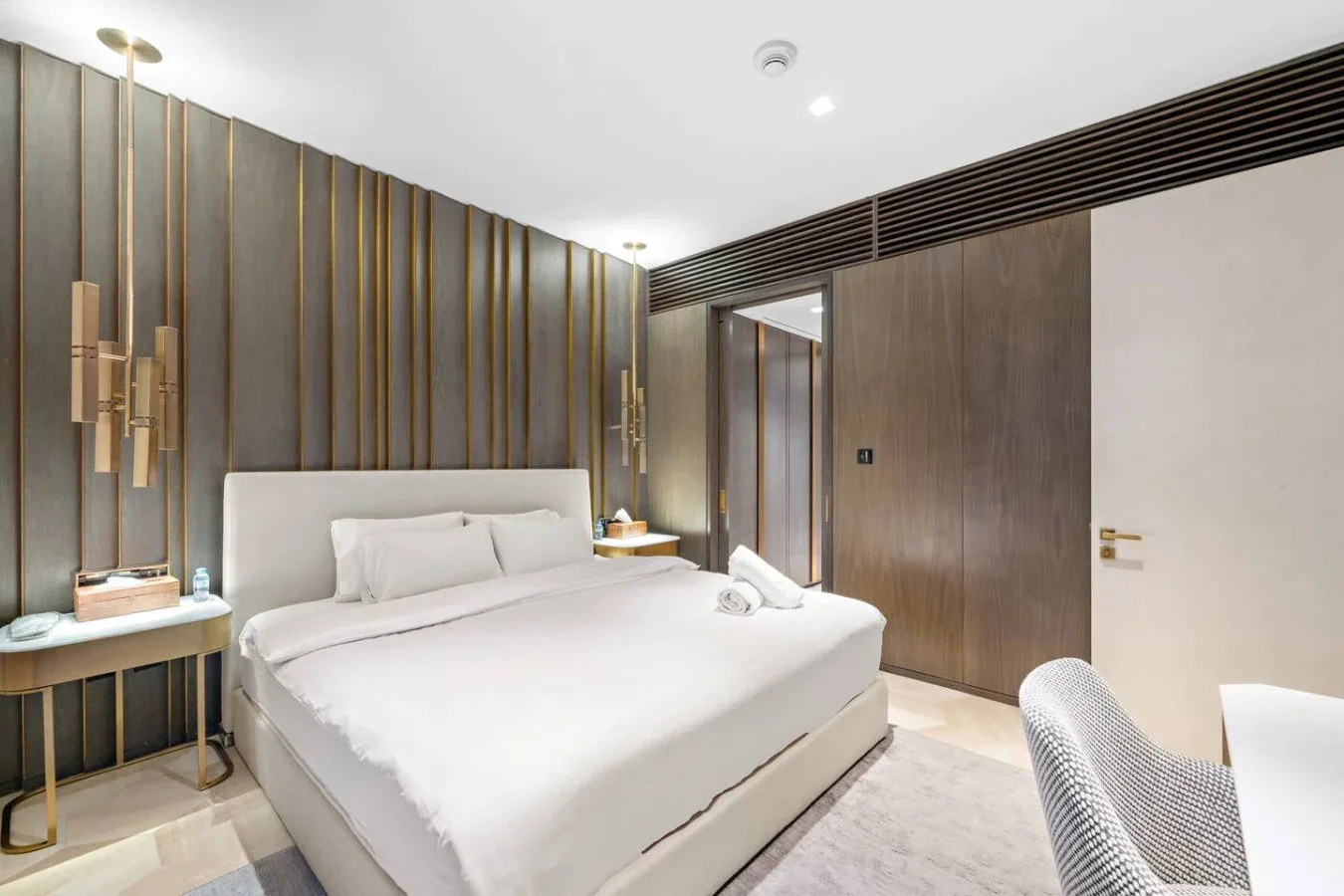 Un dormitorio con una cama bien tendida y paredes de paneles oscuros.