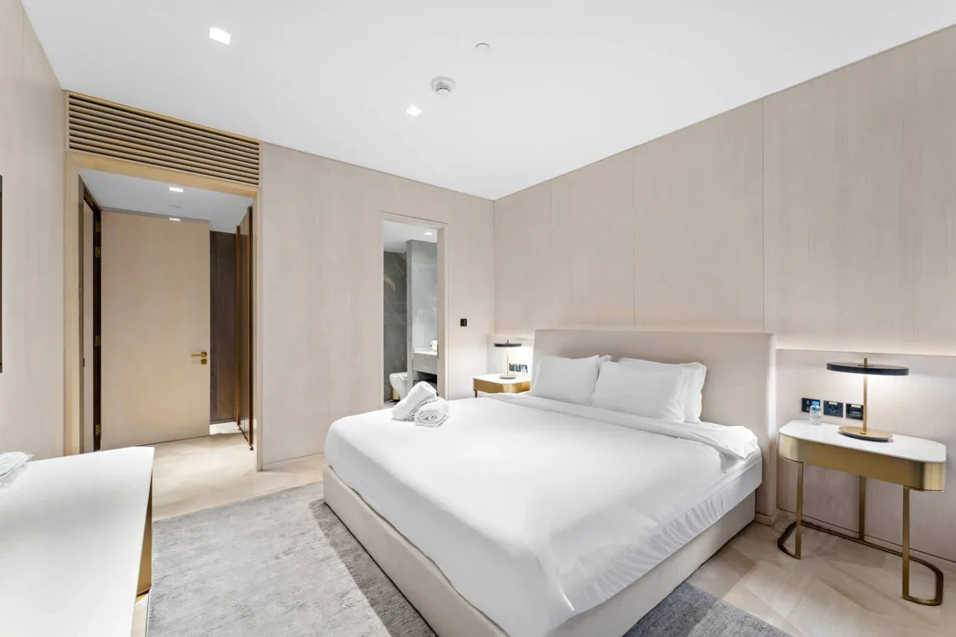 Un dormitorio luminoso con una cama bien hecha y mesas de noche.