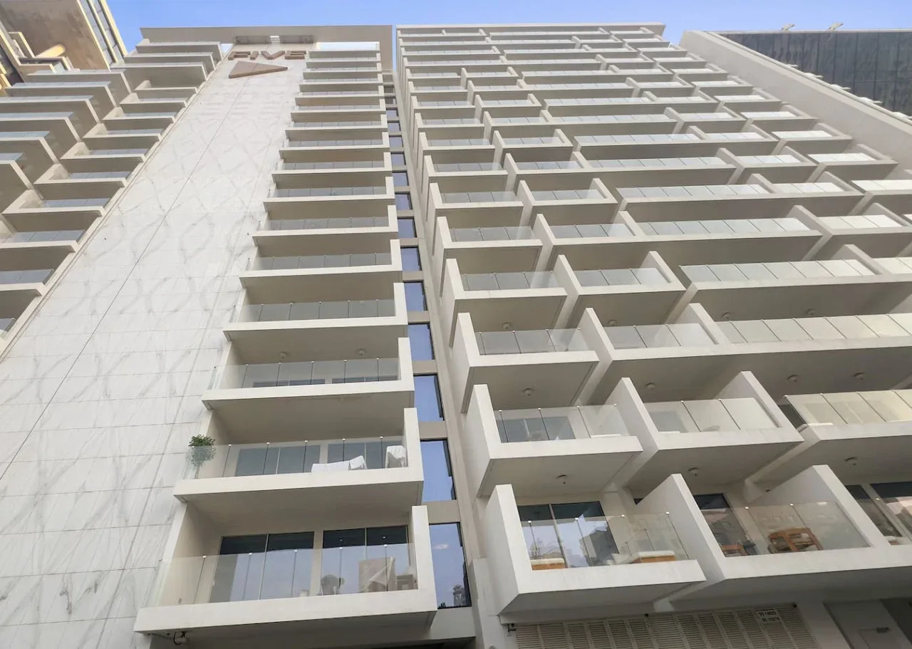 Fachada de un edificio moderno y alto con filas de balcones vista desde abajo.