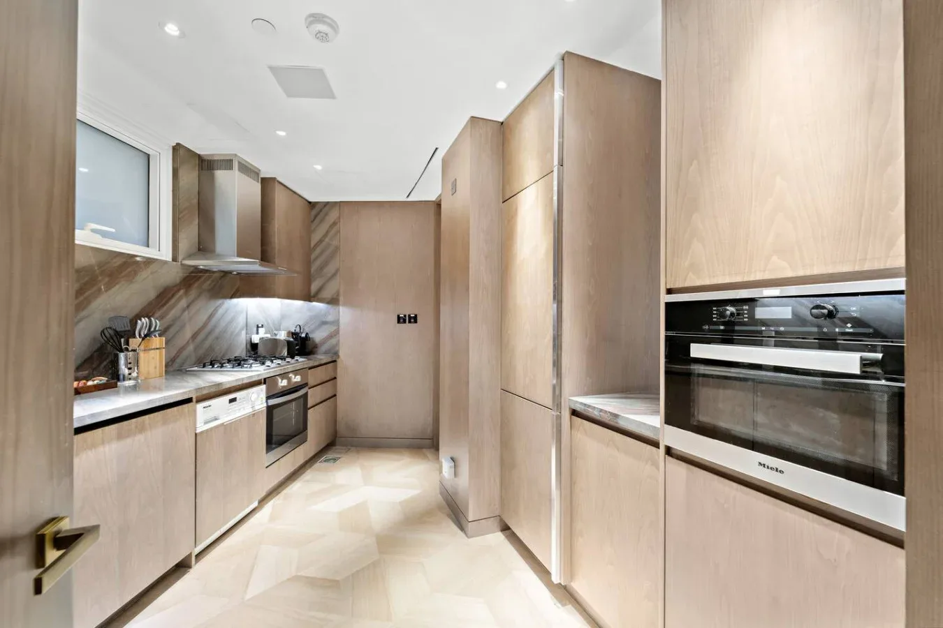 Una cocina moderna con gabinetes claros, una encimera y hornos integrados.