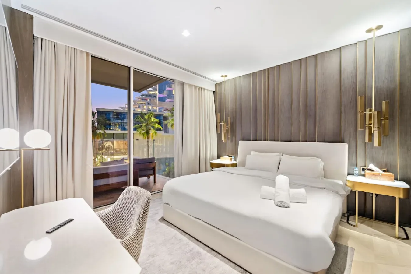 Un dormitorio luminoso con una cama grande junto a ventanales.