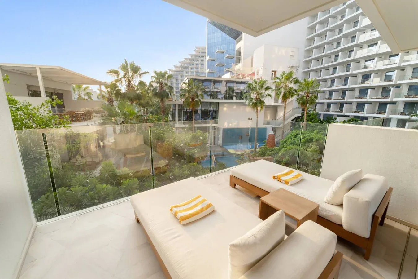Una terraza exterior tiene asientos acolchados con vistas a jardines y edificios cercanos.