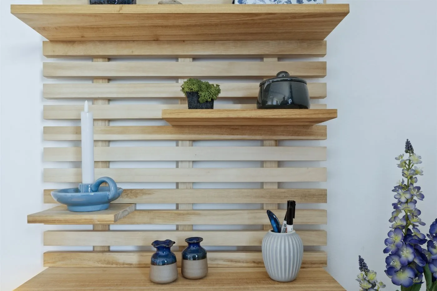 Estantes de cocina de madera con recipientes pequeños y flores decorativas.