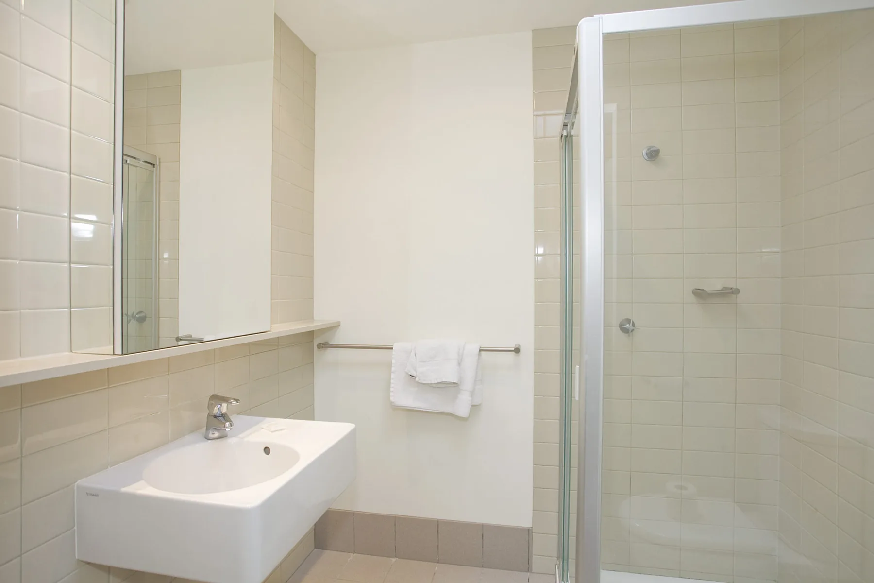 A tiled bathroom with a sink and glass shower.