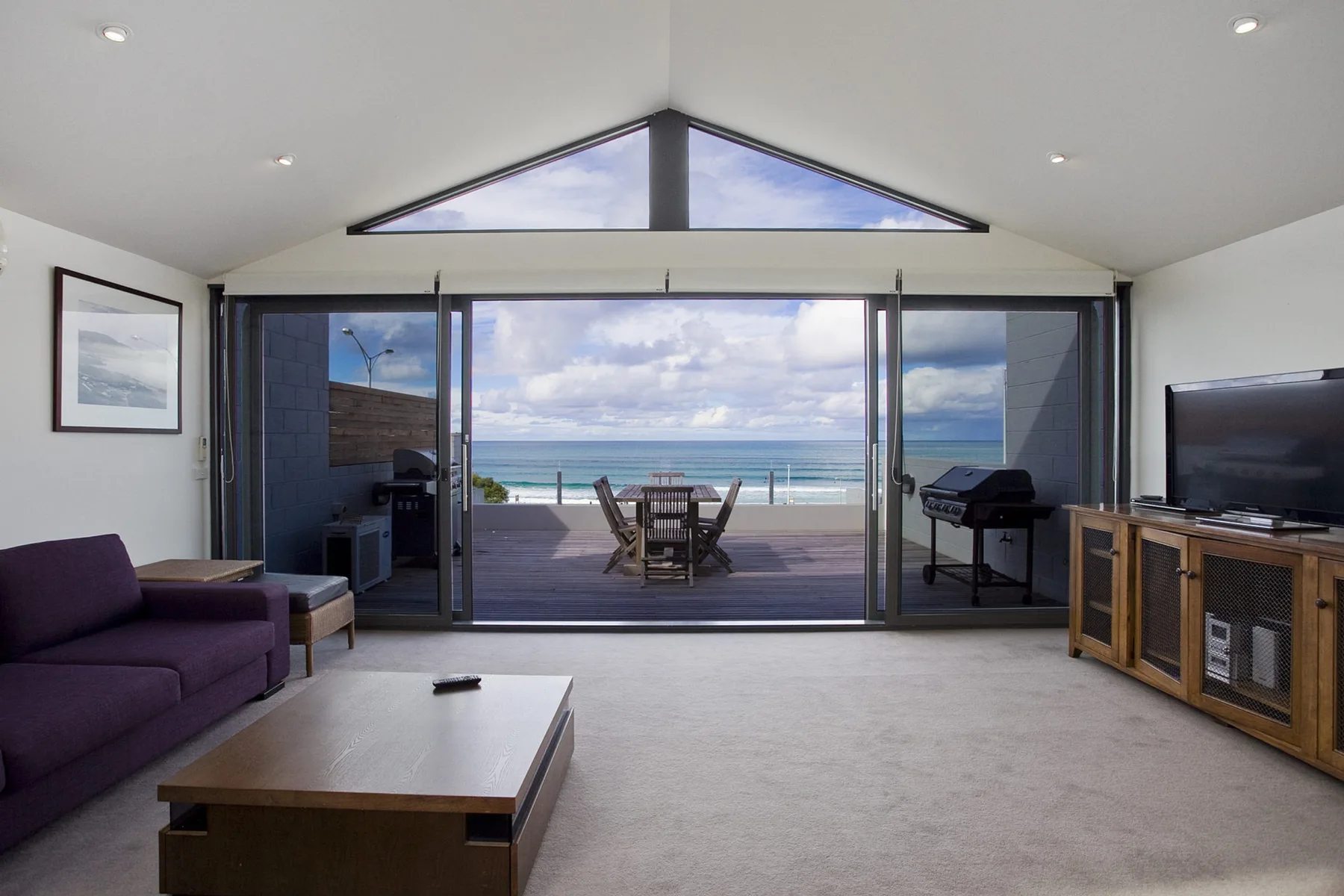 A living room opens onto a patio with ocean views.