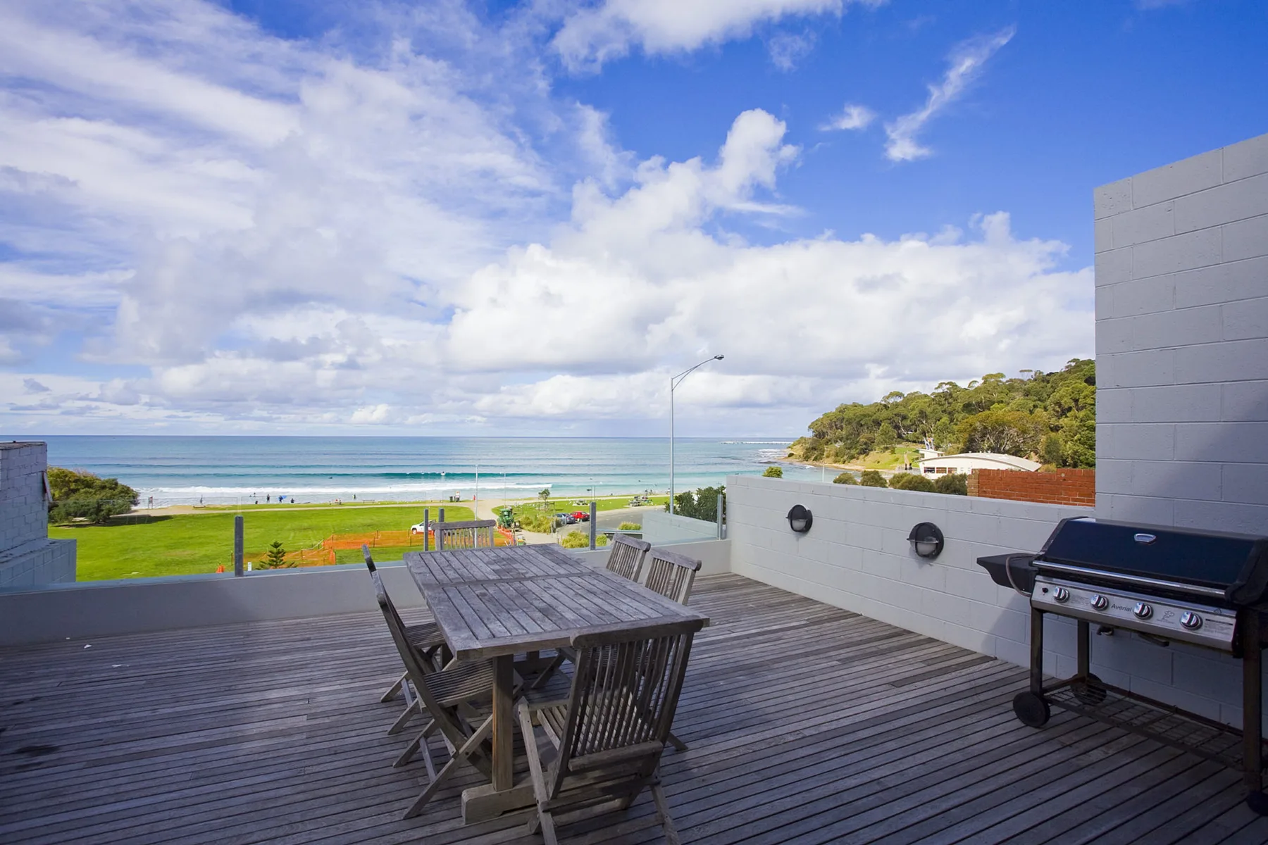 A rooftop dining terrace overlooks the ocean, with outdoor seating and a barbecue.