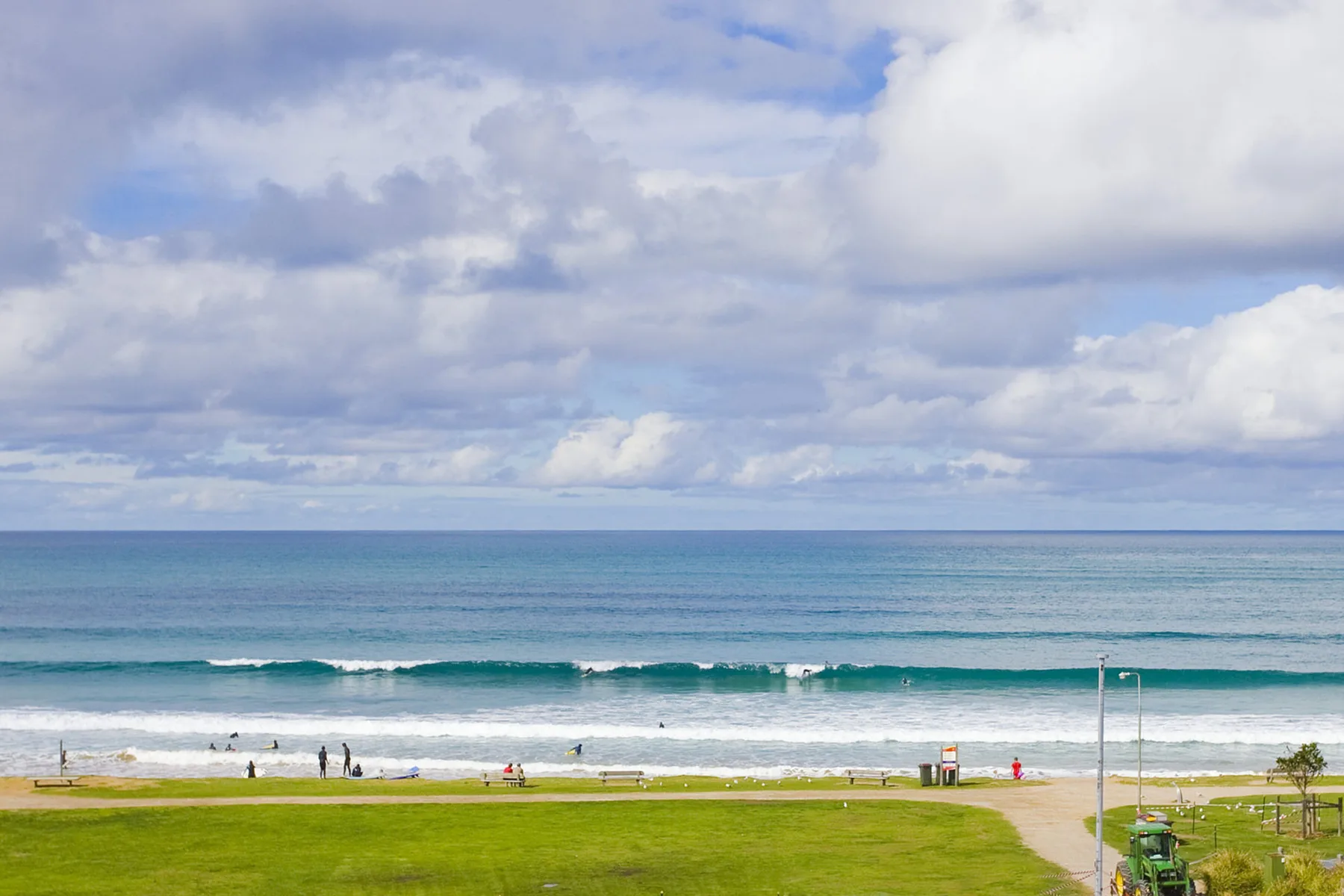 A coastal beach with gentle waves beneath a cloudy sky.