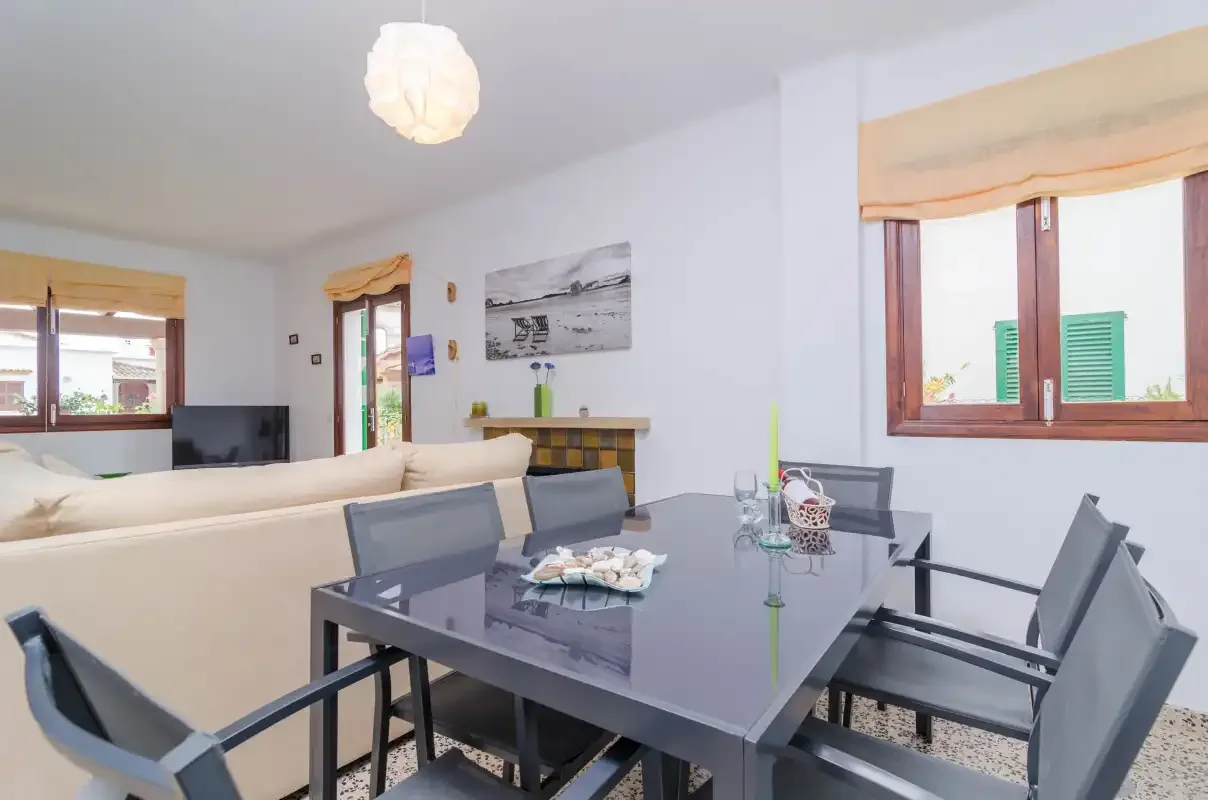 A dining area with a glass table and seating beside large windows.