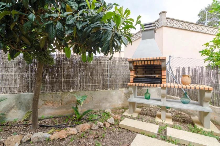 An outdoor garden area with a brick barbecue beside a leafy tree.