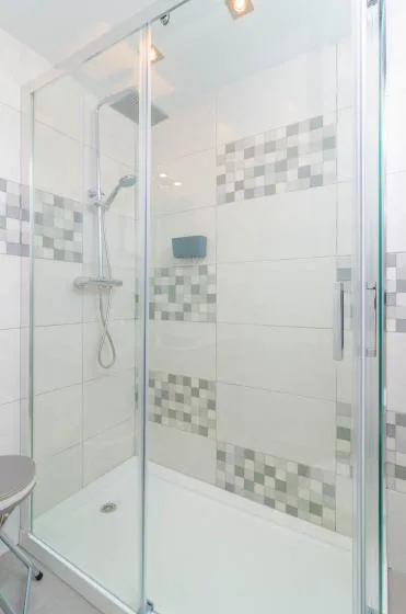 A tiled bathroom shower with glass panels and a wall-mounted showerhead.