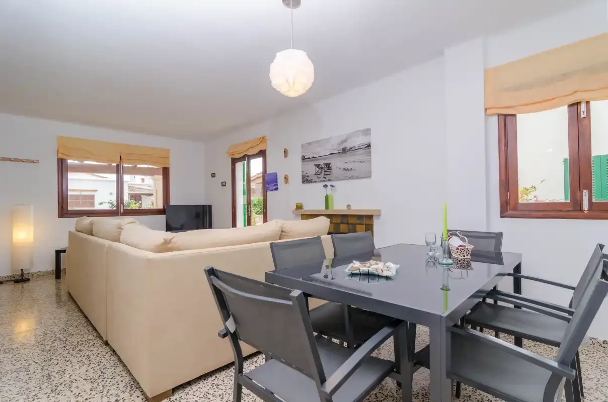 A living and dining area with seating, a dining table, and windows.