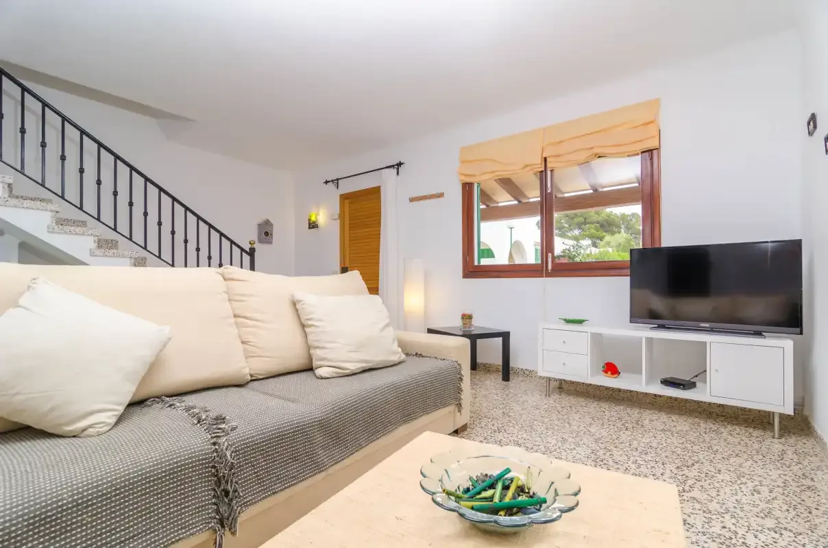A living room with a sofa, television, and staircase.