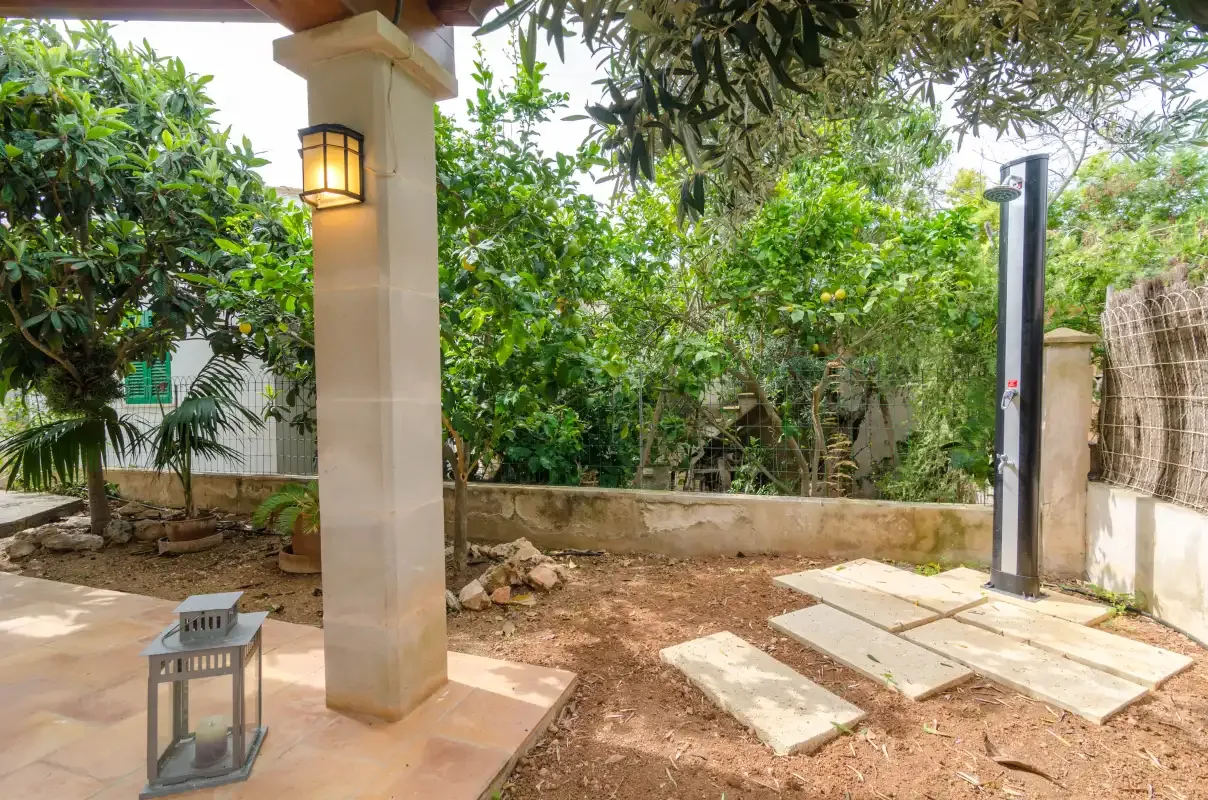 A shaded patio opens onto a leafy garden with a paved walkway.