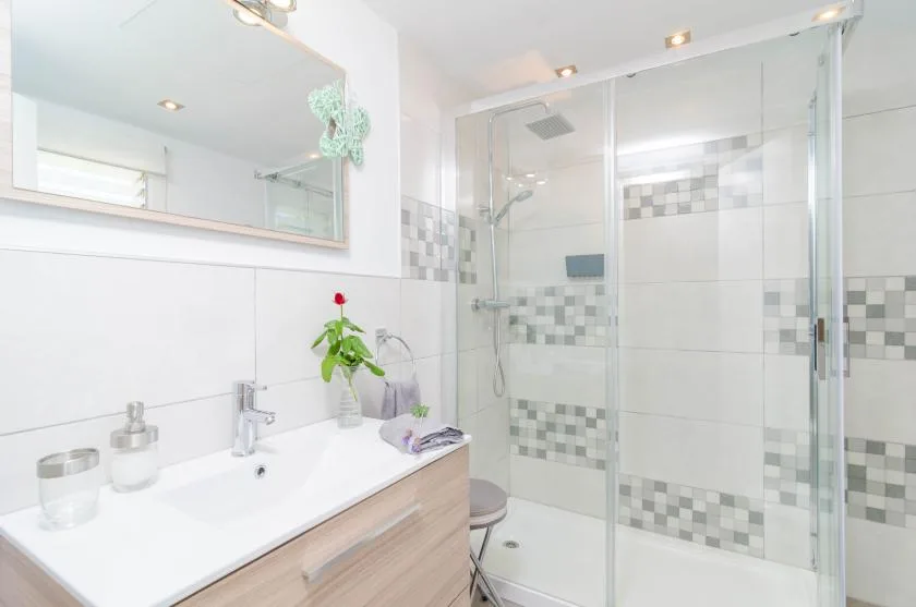 A bright bathroom with a sink and glass-enclosed shower.