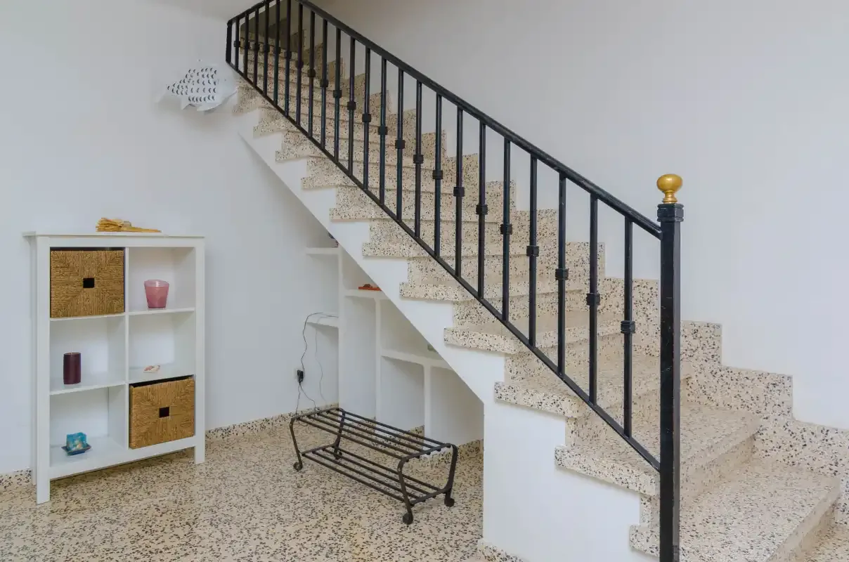 A staircase with a black railing rises above a small entry area.