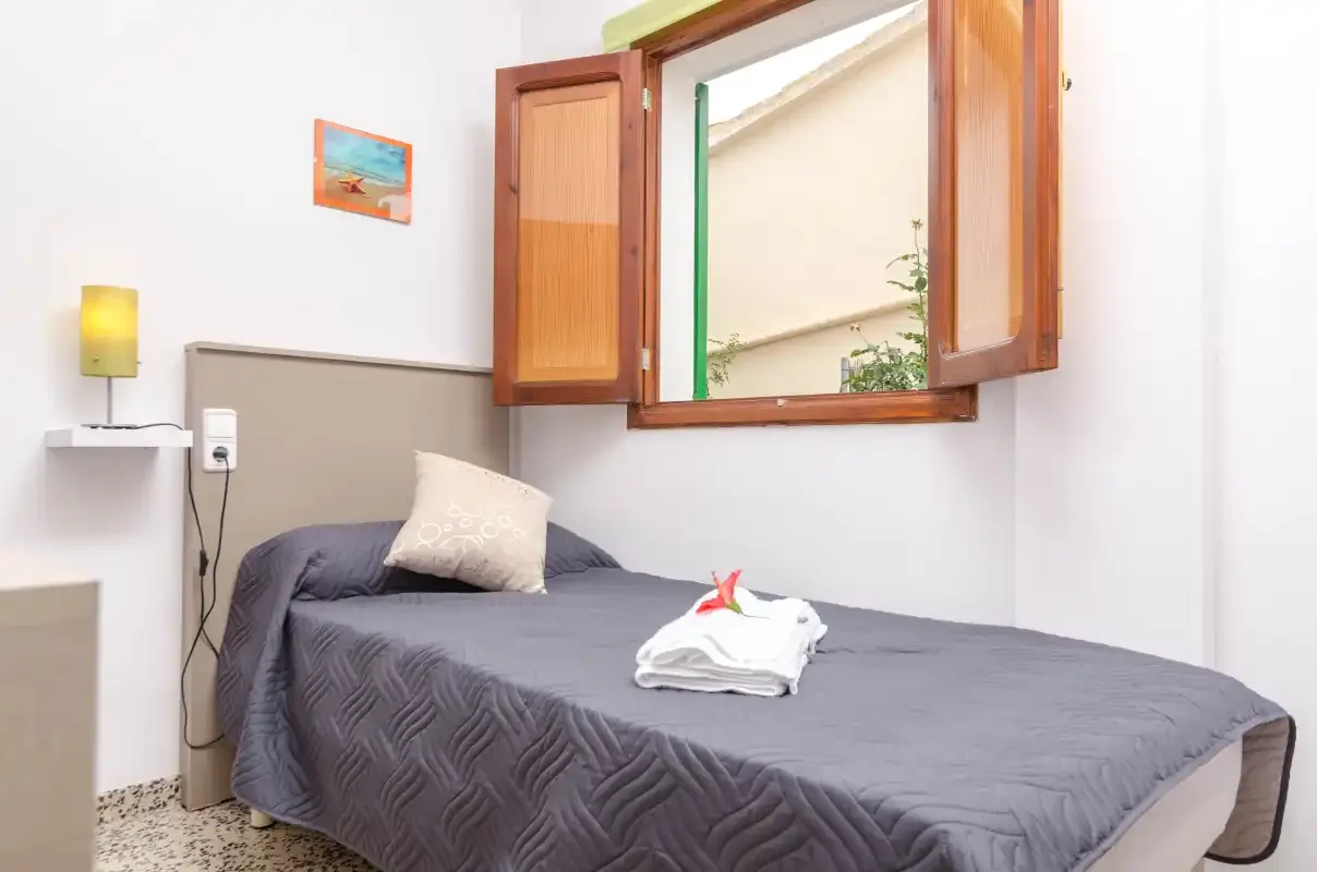 A bedroom with a bed beneath an open window.