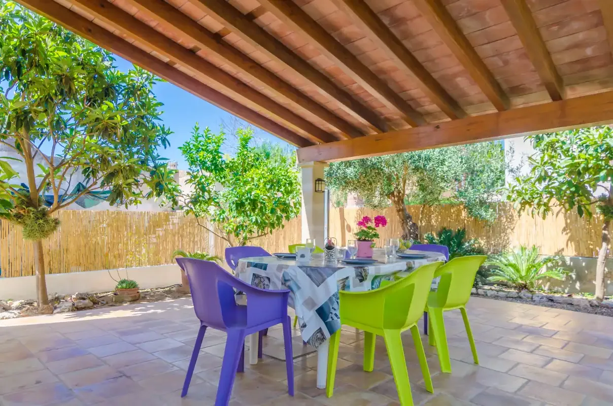 A shaded outdoor dining area with a table and colorful seating.