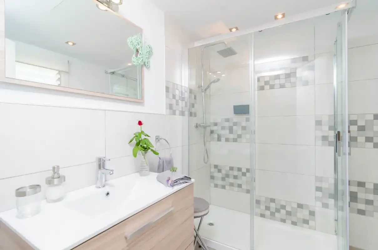 A bright bathroom with a sink and glass shower.